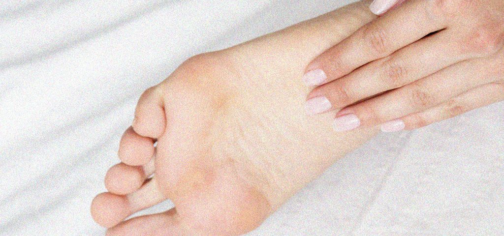 planta dos pés sendo massageada por uma das mãos